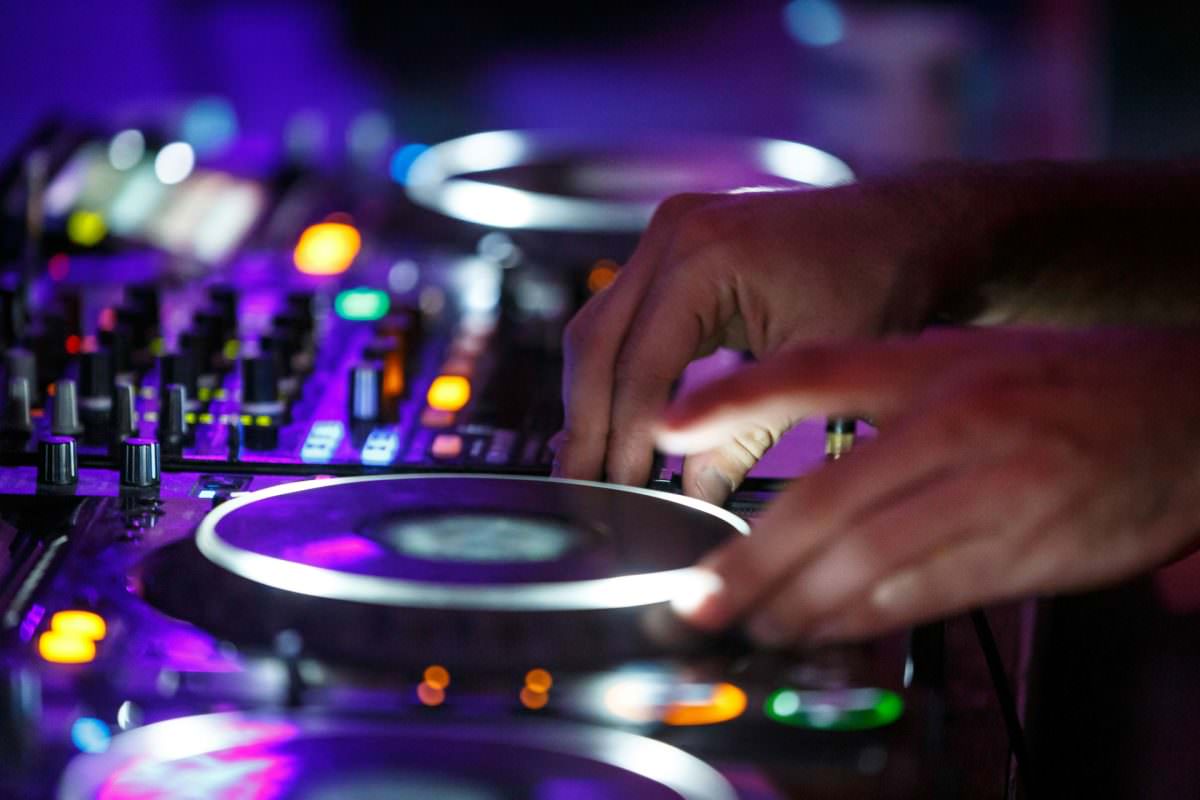 die Hände eines DJs bedienen die Regler an seinem Mischpult