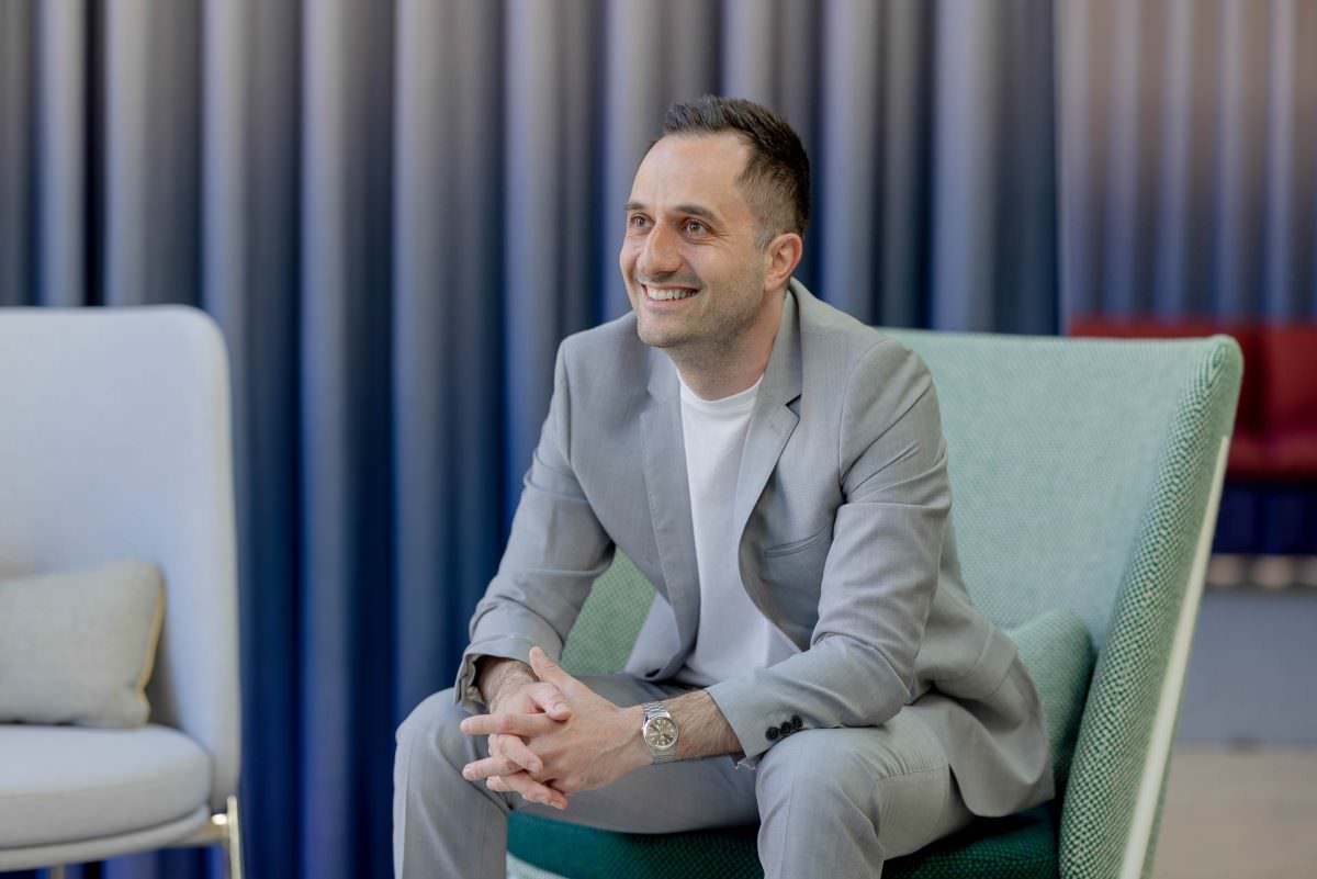 fürs Portrait sitzt DJ Carlos auf einem grünen Stuhl