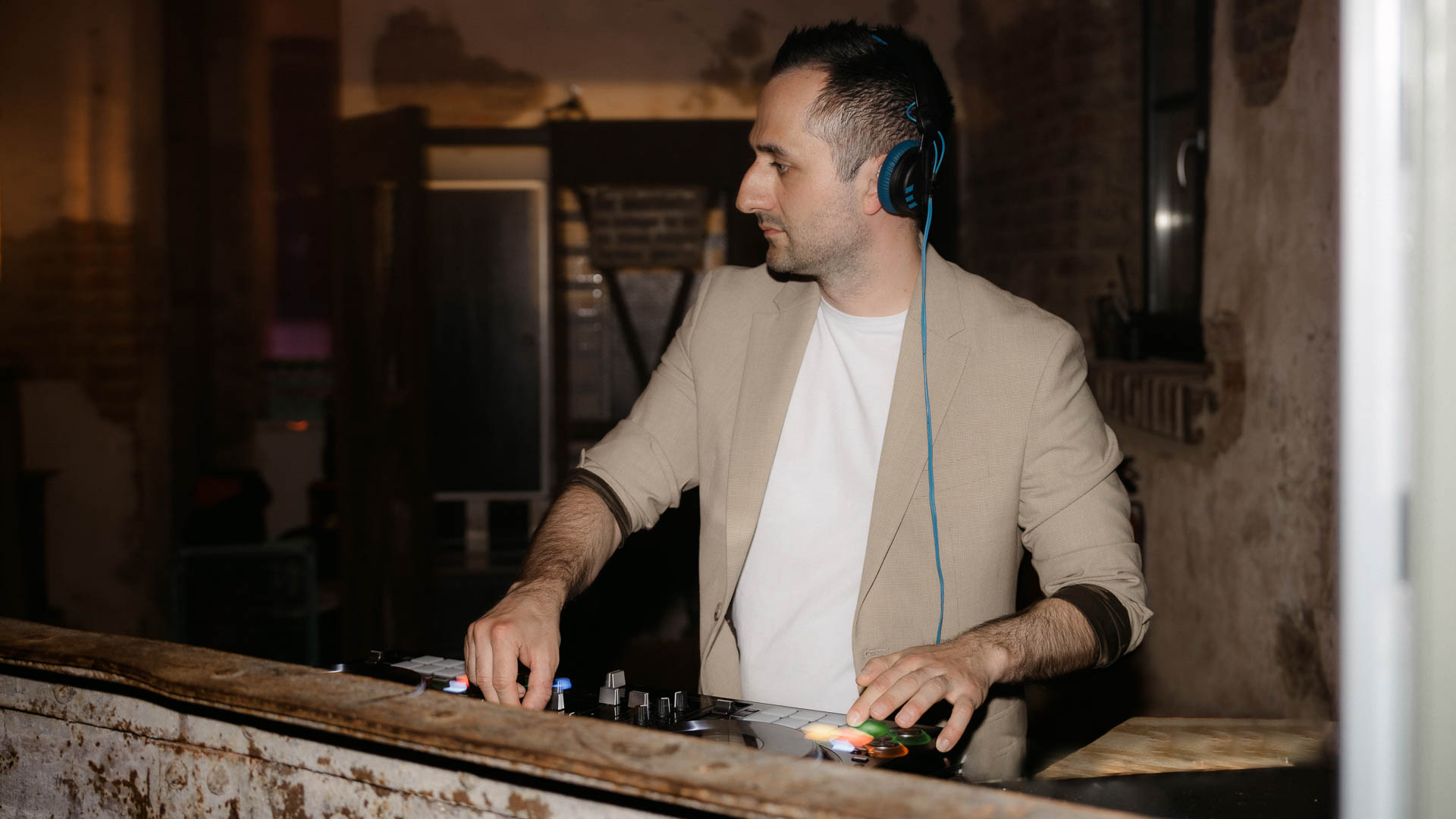 DJ Carlos steht bei einem Event hinter seinem DJ Pult und bedient die Regler