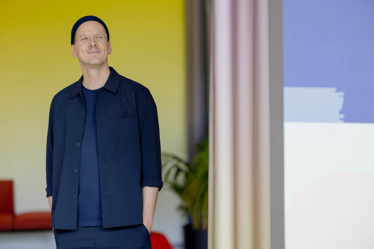 For the portrait shot, DJ Phil has his hands in his pockets and is standing in front of a yellow wall.