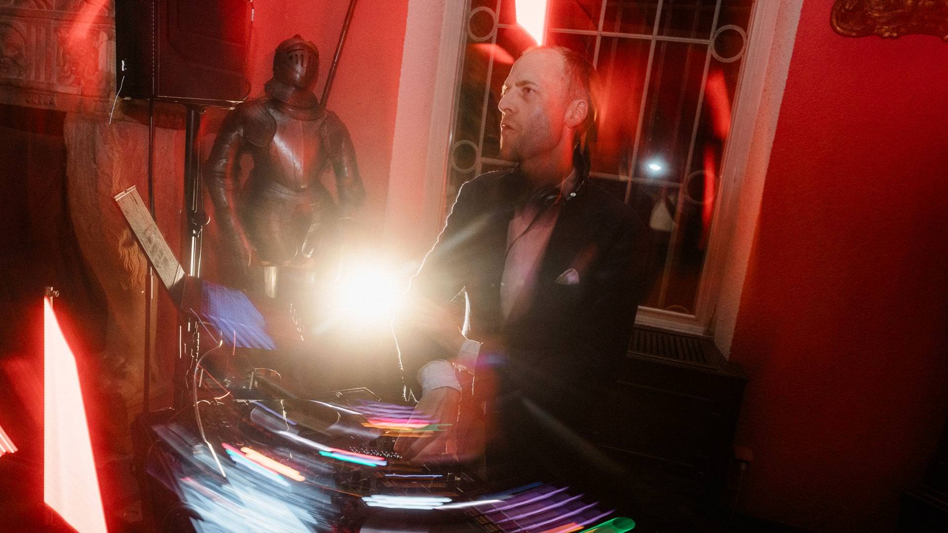 DJ Tobi is at the controls on the mixing desk at a party.