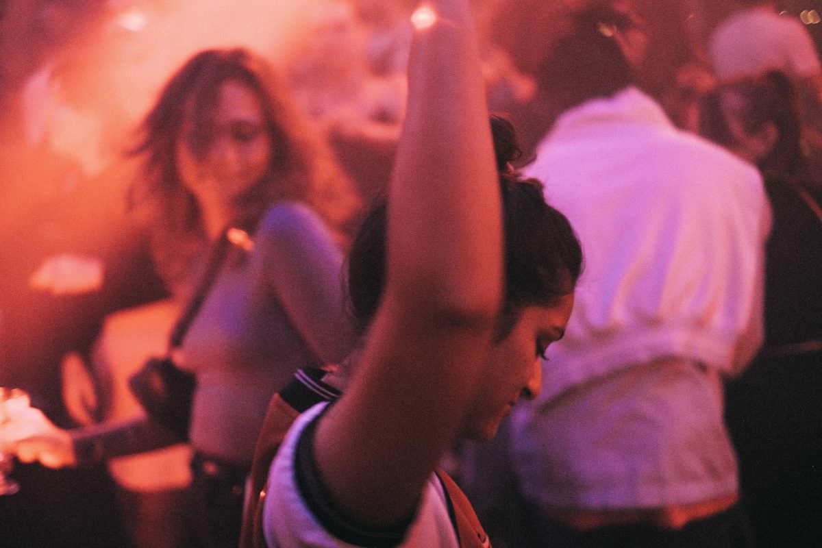 eine Frau tanzt auf einer Party ausgelassen mit den Armen in der Luft
