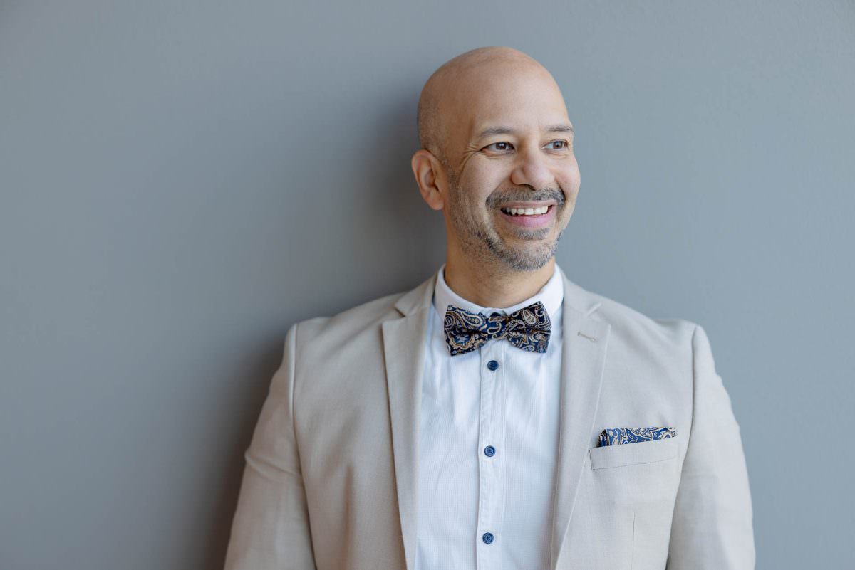 Close-up portrait of DJ Viru standing in front of a grey wall