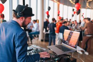 Close-up of DJ Markus Rosenbaum at his modern DJ setup at an after-trade fair event in Cologne.