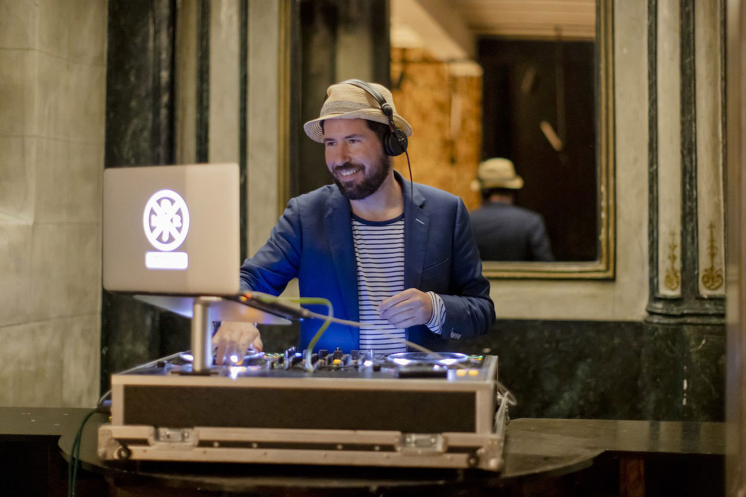 Der professionelle Event-DJ Markus Rosenbaum steht bei einer Firmenfeier hinter seinem DJ-Pult.