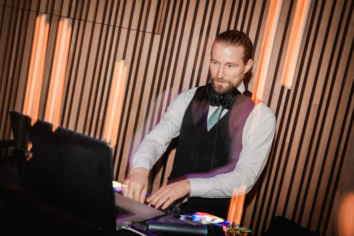 Event-DJ Jean-Philippe steht bei einer Firmenveranstaltung hinter seinem Mischpult