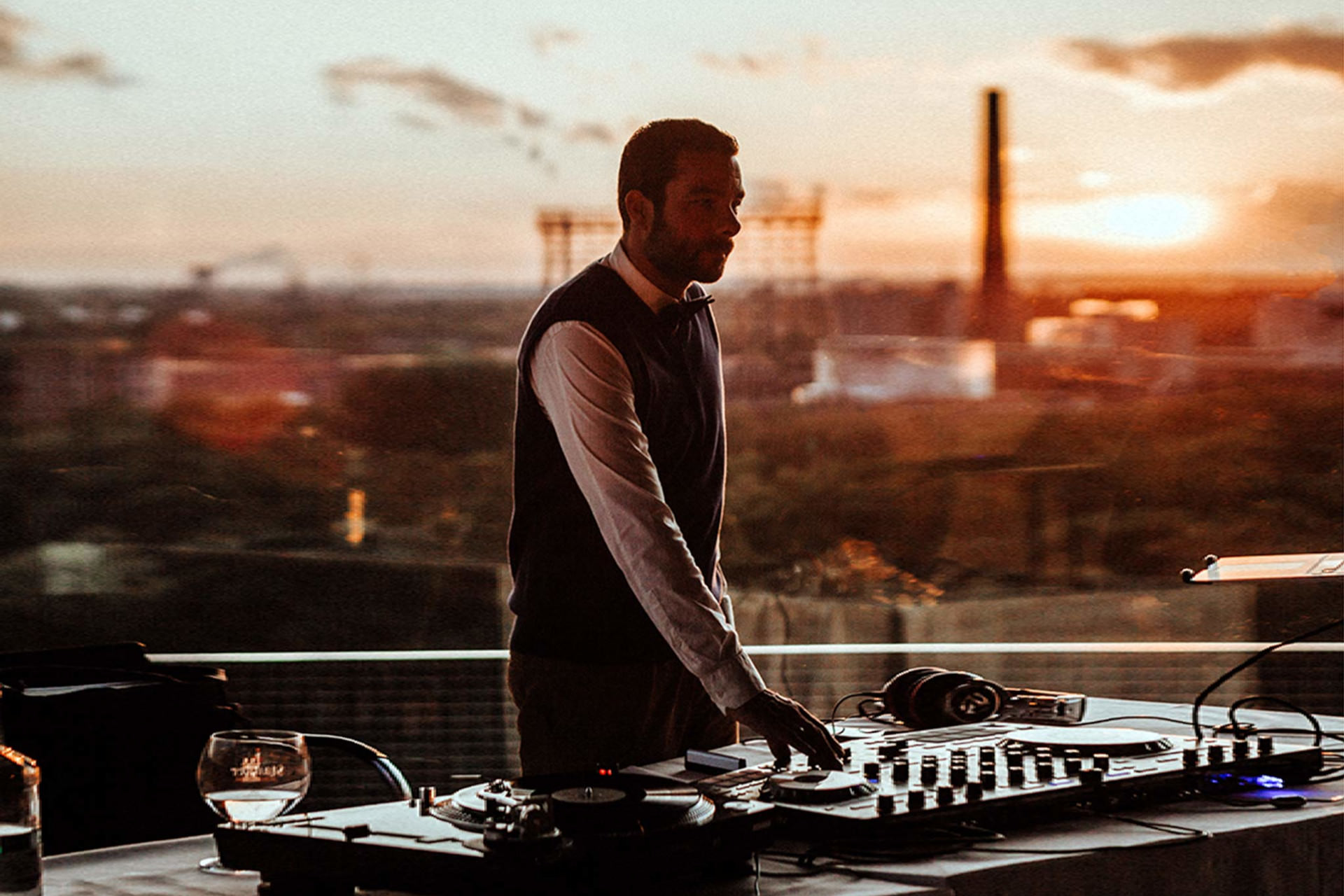 DJ Matthias steht bei einem Open Air Event hinter seinem Pult.