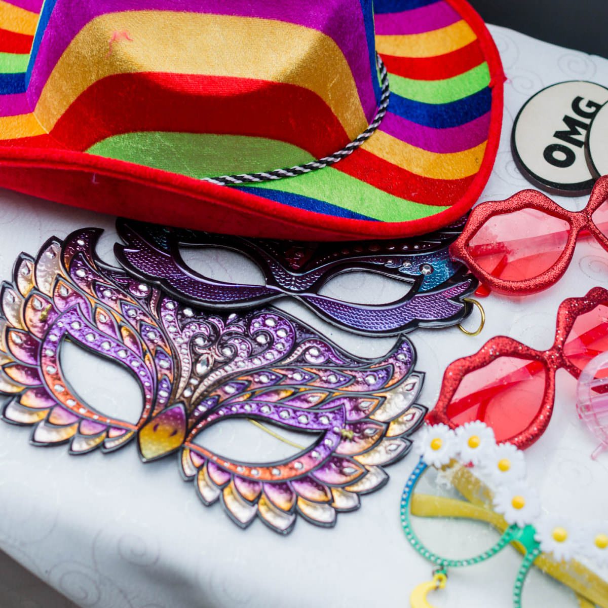 Photo booth props such as masks, funny glasses, signs and a colourful hat