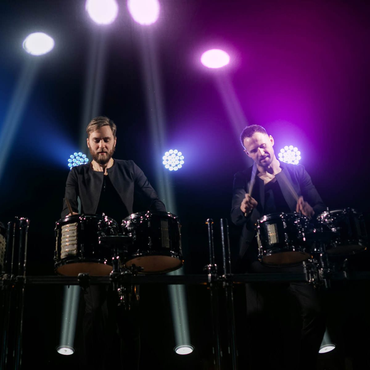 Two men playing percussion in the spotlight
